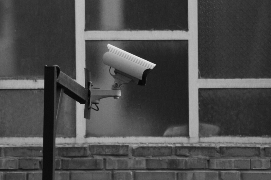 Monochrome image of a CCTV camera mounted on a building exterior.