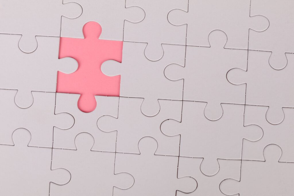 Close-up of an unfinished puzzle with a pink missing piece, highlighting emptiness.