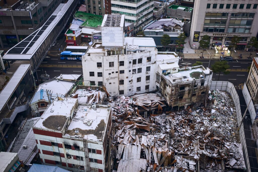 Aerial shot of a demolished building amidst cityscape, showcasing urban decay and reconstruction.